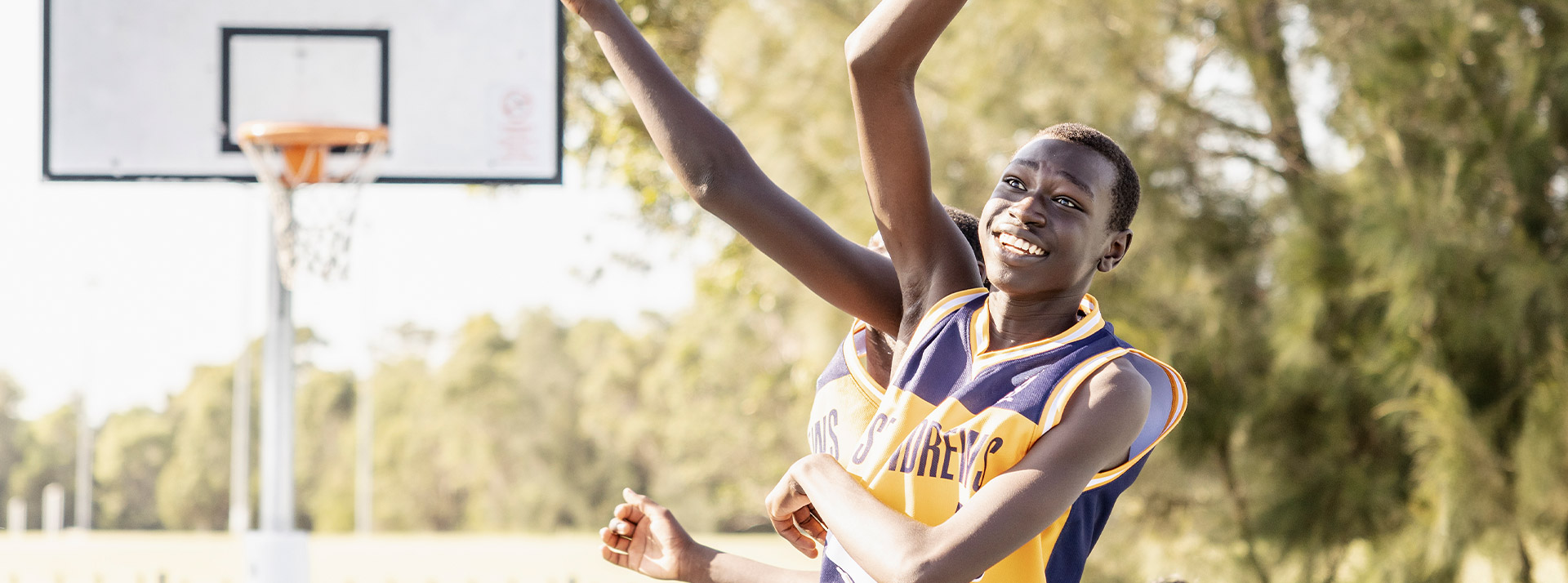 Student playing basketball on the basketball courts at St Andrews College Marayong