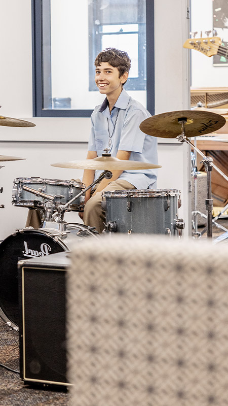 Student playing the drums in the classroom at St Andrews College Marayong