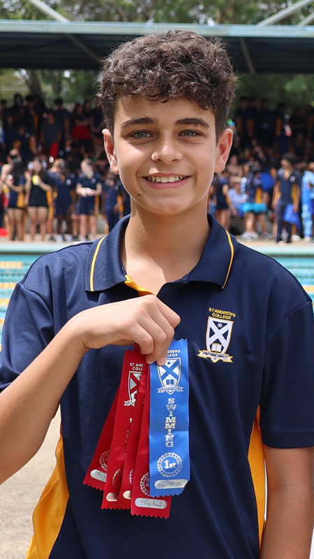 Students holding their place ribbons they earned at the St Andrews College Marayong swimming carnival