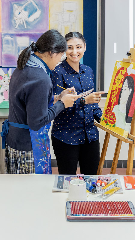 Teacher and her student working on an artwork in the classroom at St Andrews College Marayong