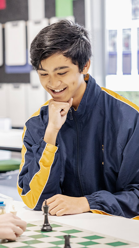 Student smiling in the library at St Andrews College Marayong
